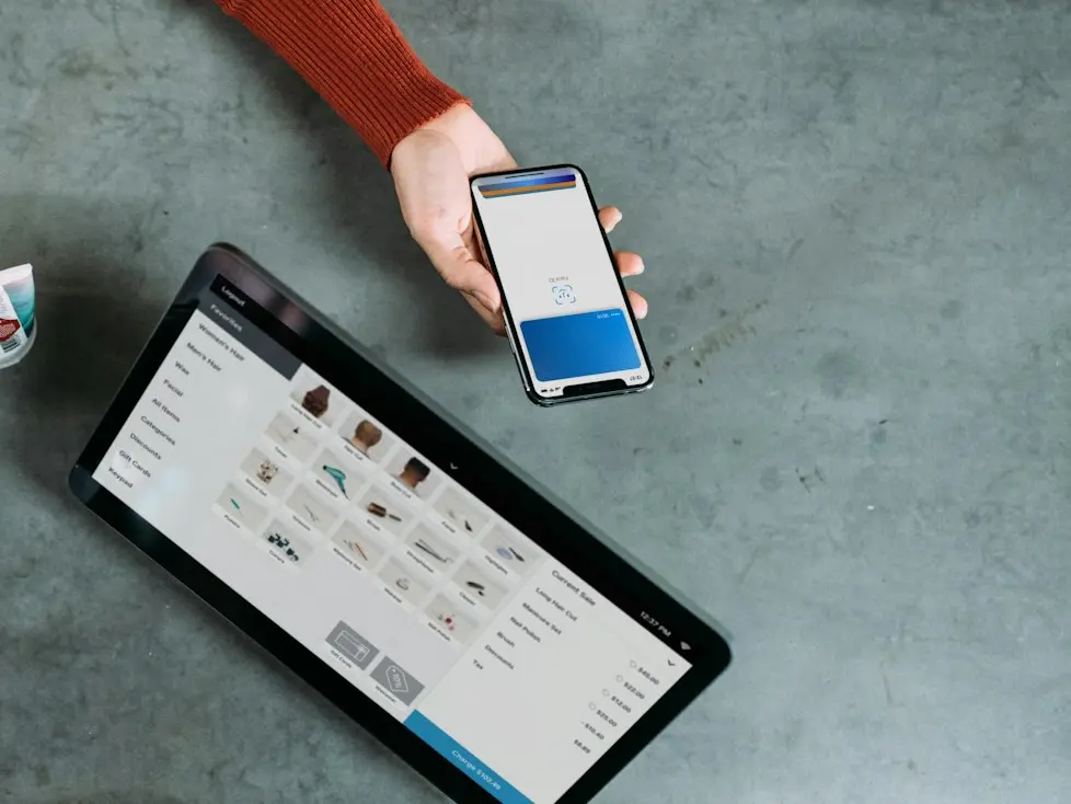 person holding smartphone beside tablet computer